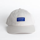 Front view of an Avelamer Bridgeway Cap in Mainsail (off-white) with a navy Avelamer brand woven label on the front panel