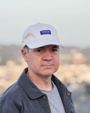 Man wearing an Avelamer Bridgeway Cap in Mainsail (off-white) with navy Avelamer woven brand label on the front