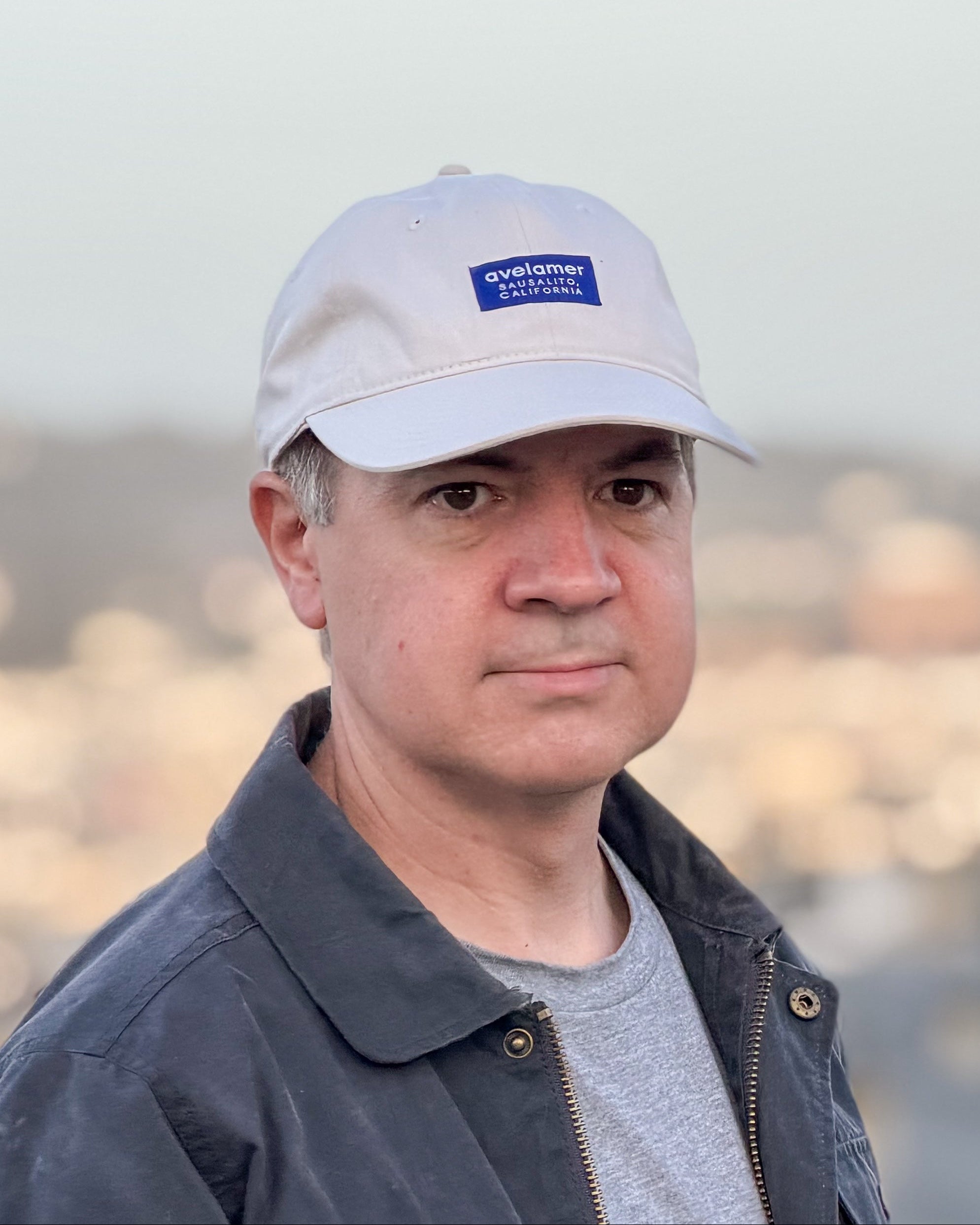 Man wearing an Avelamer Bridgeway Cap in Mainsail (off-white) with navy Avelamer woven brand label on the front