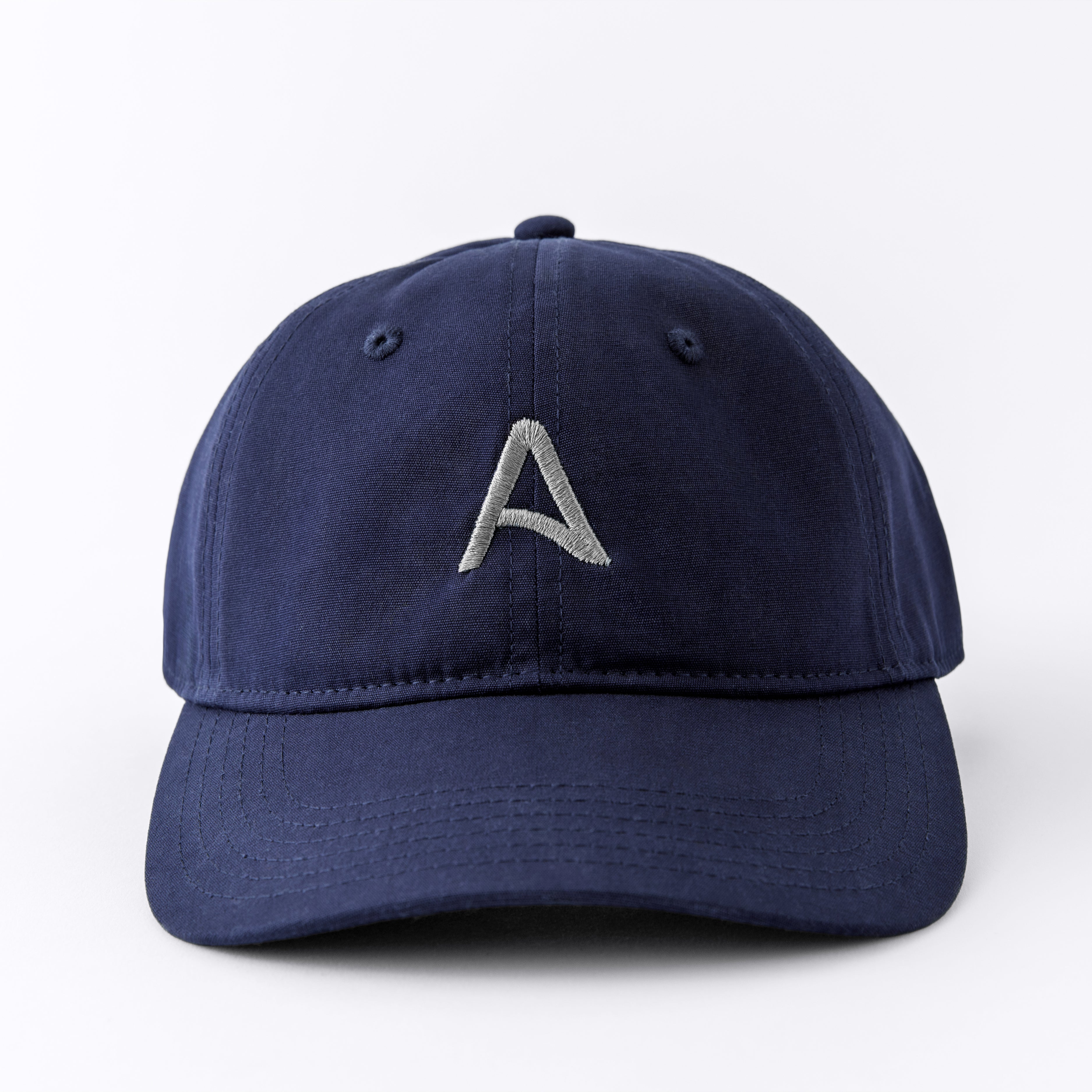 Front view of an Avelamer Caledonia Cap in Deepwater navy with embroidered gray A-flag logo on a white background