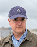 Man wearing a cap with a logo and jacket outdoors