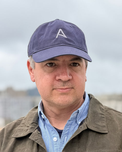 Man wearing a cap with a logo and jacket outdoors