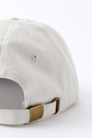 Back view of an Avelamer Caledonia Cap in Mainsail off-white with a gold buckle on a white background
