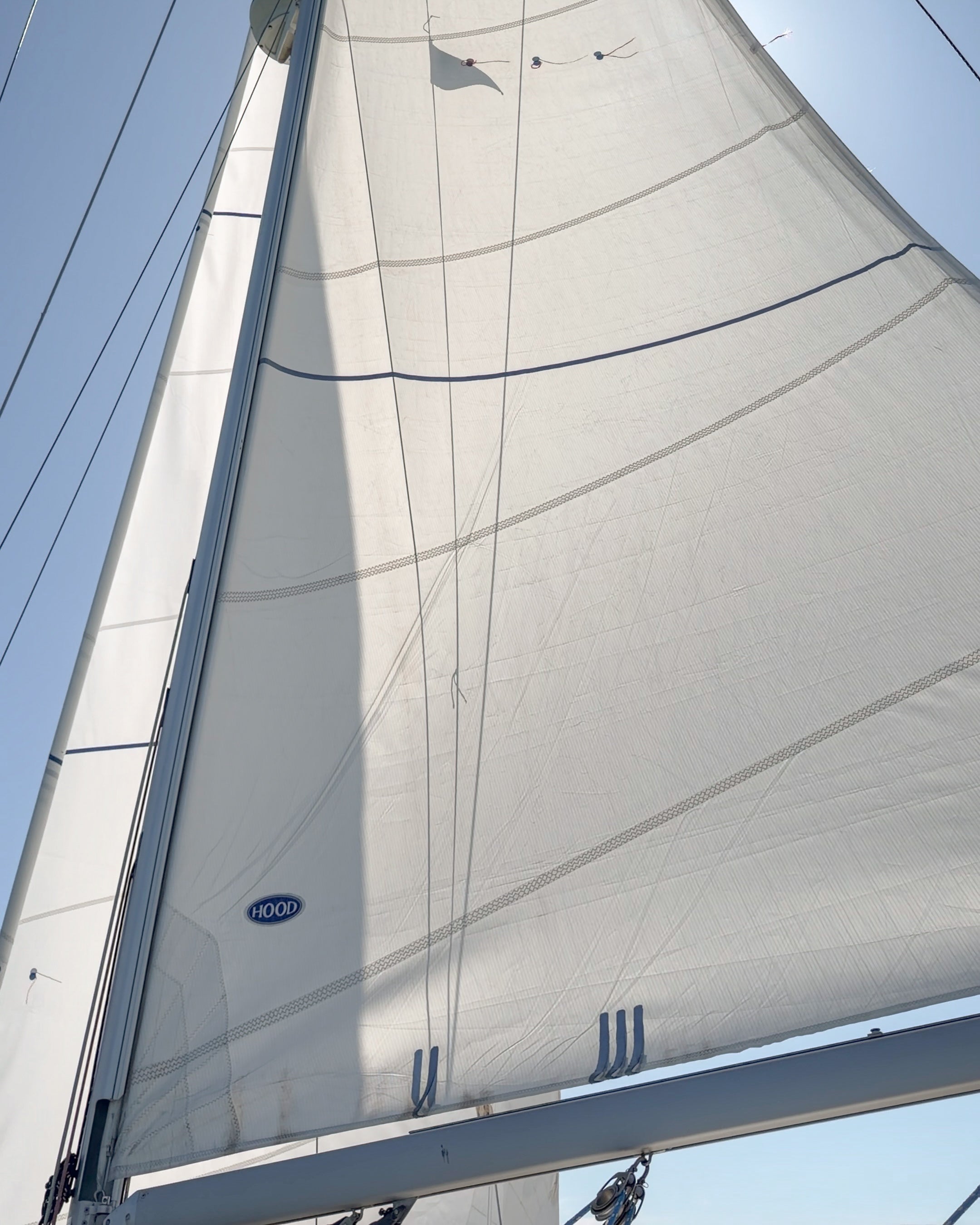 Close-up of a white mainsail against a clear blue sky