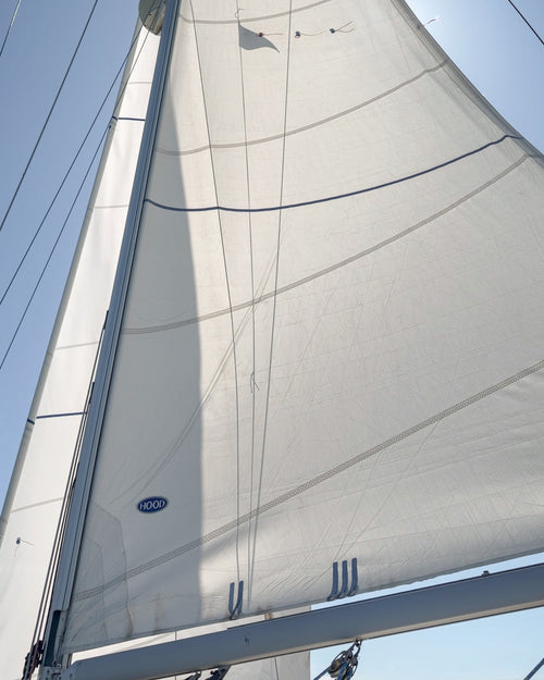 Close-up of a white mainsail against a clear blue sky