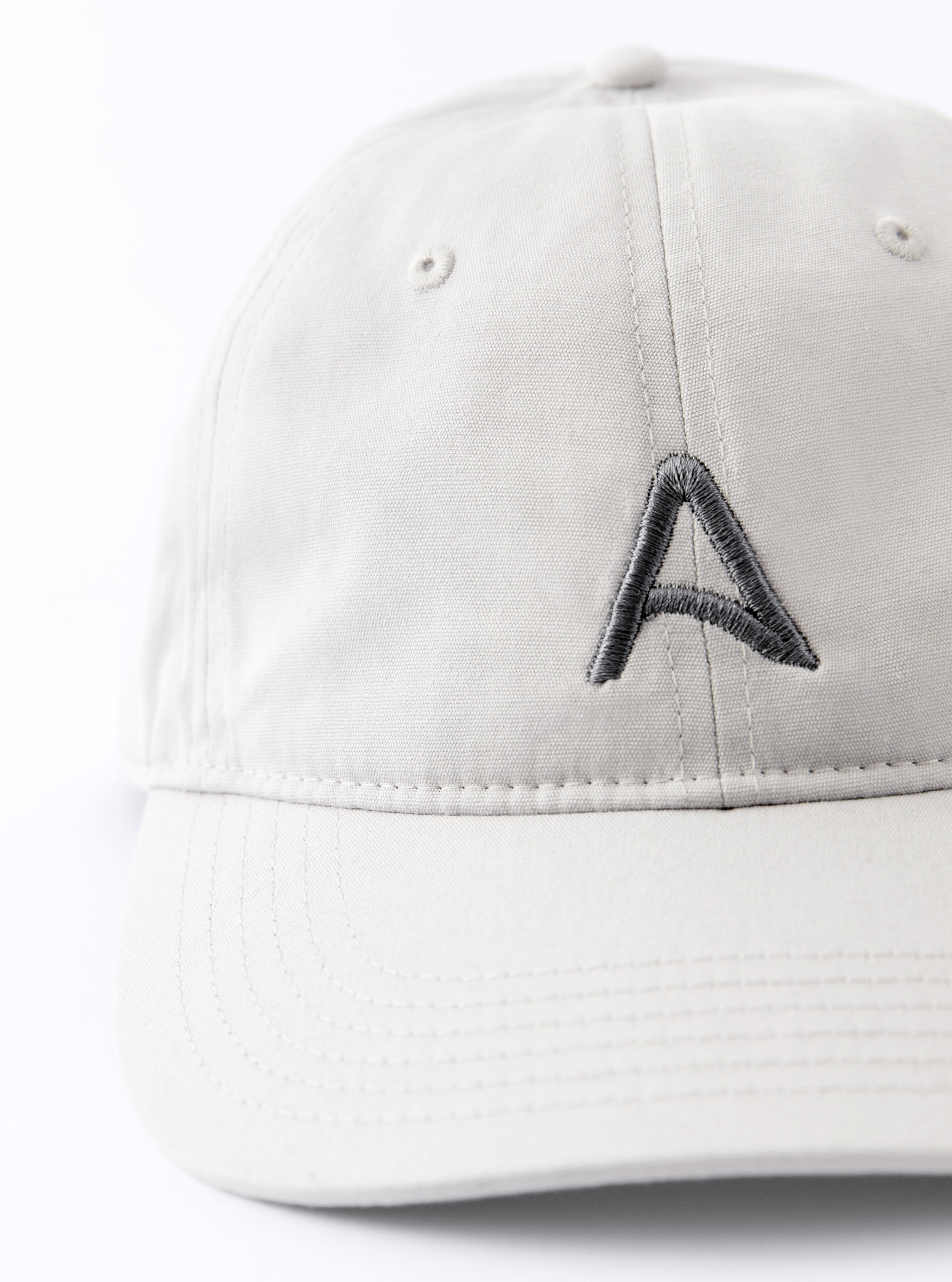Front view of an Avelamer Caledonia Cap in Mainsail off-white with embroidered gray A-flag logo on a white background