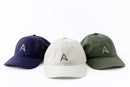 Trio of Avelamer Caledonia Caps in Deepwater navy, Mainsail off-white, Cypress Grove green with gray embroidered A-flag logos visible against a white background.