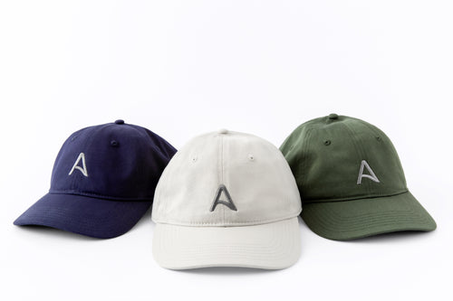 Trio of Avelamer Caledonia Caps in Deepwater navy, Mainsail off-white, Cypress Grove green with gray embroidered A-flag logos visible against a white background.
