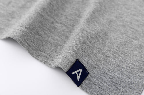 Close-up of Avelamer Ebbide Tee in Morning Fog heather gray with blue A-flag logo woven hem label