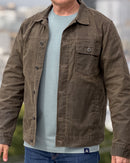 Man wearing an olive jacket over a light blue-green shirt with a blurred background