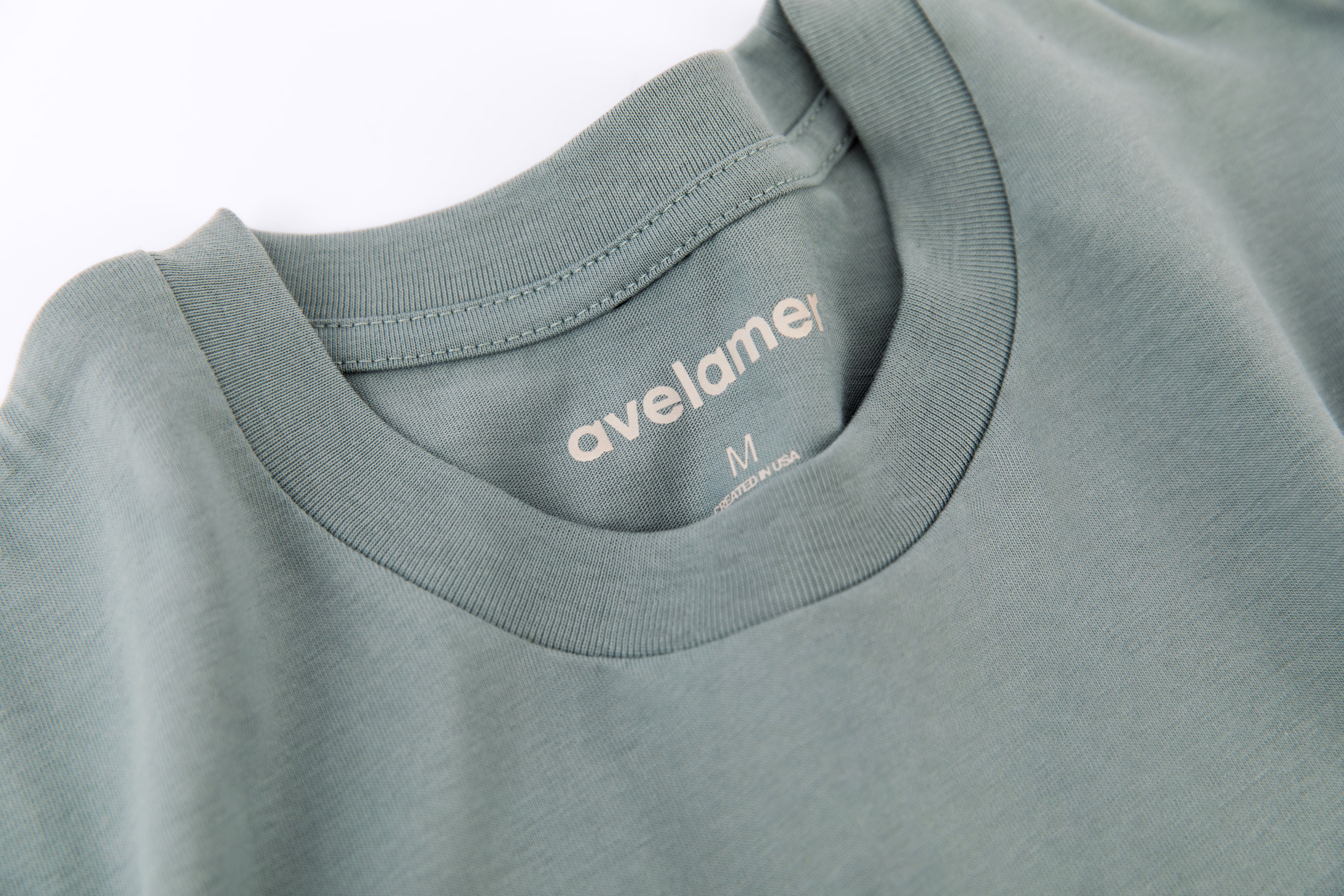 Close-up of Avelamer Ebbtide Tee in Shallow Bay blue-green with printed neck label