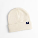 Avelamer Harbor Beanie in Mainsail off-white with blue A-flag logo woven cuff label laid flat on a white background