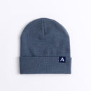 Avelamer Harbor Beanie in Ocean Slate blue-gray with blue A-flag logo woven cuff label laid flat on a white background