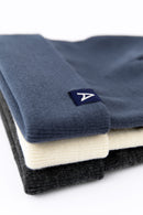 Stack of three beanies in blue-gray, off-white, and charcoal on a white background.