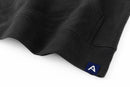 Close-up of Avelamer Sausalito Hoodie in Headland Shadow dark gray with blue A-flag logo woven hem label on a whtie background