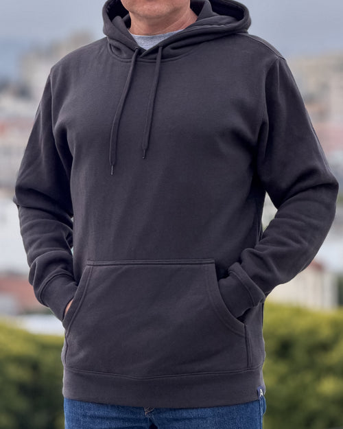 Man in dark gray hoodie with blurred city background