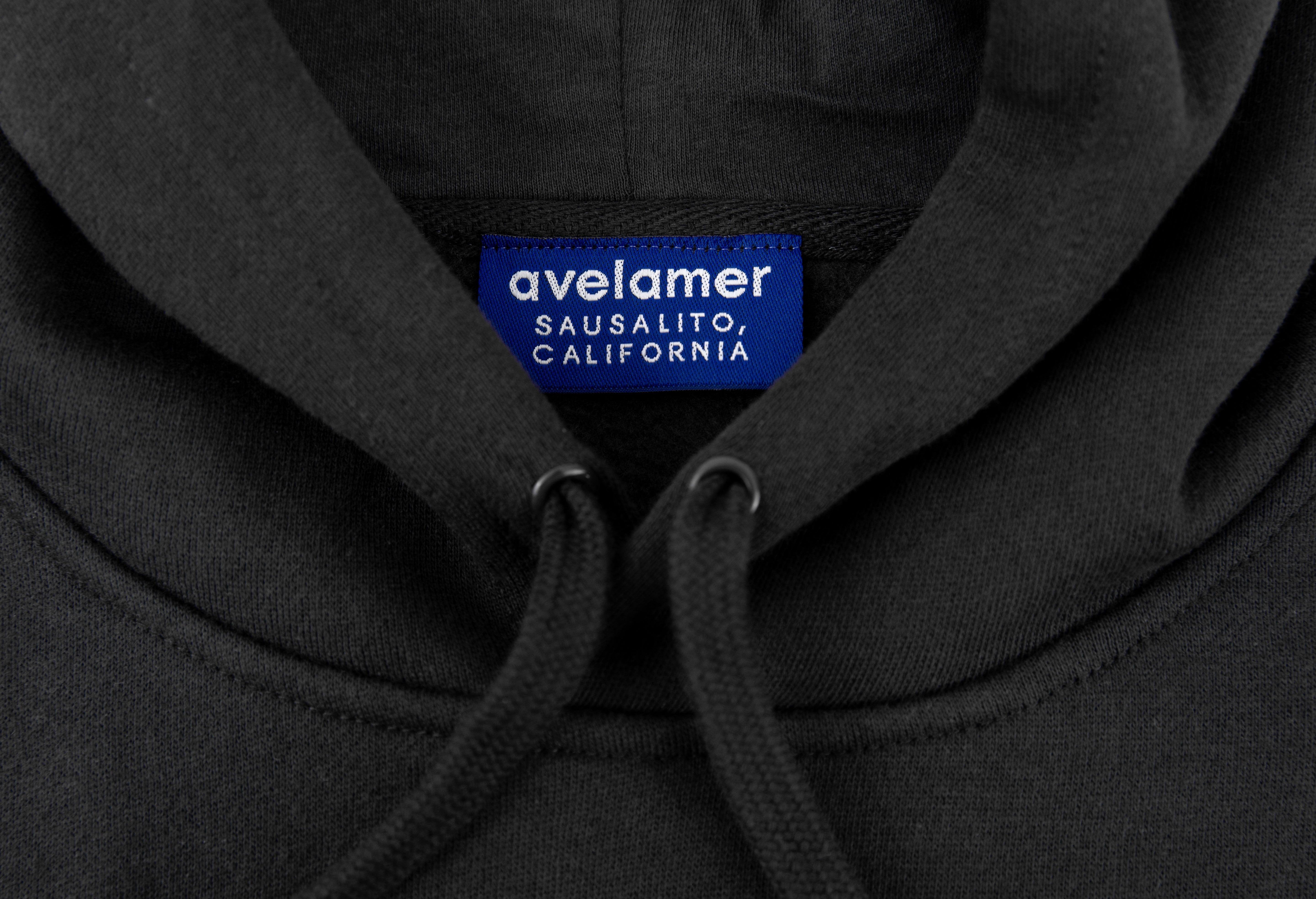 Close-up of Avelamer Sausalito Hoodie in Headland Shadow dark gray with a woven branded neck label
