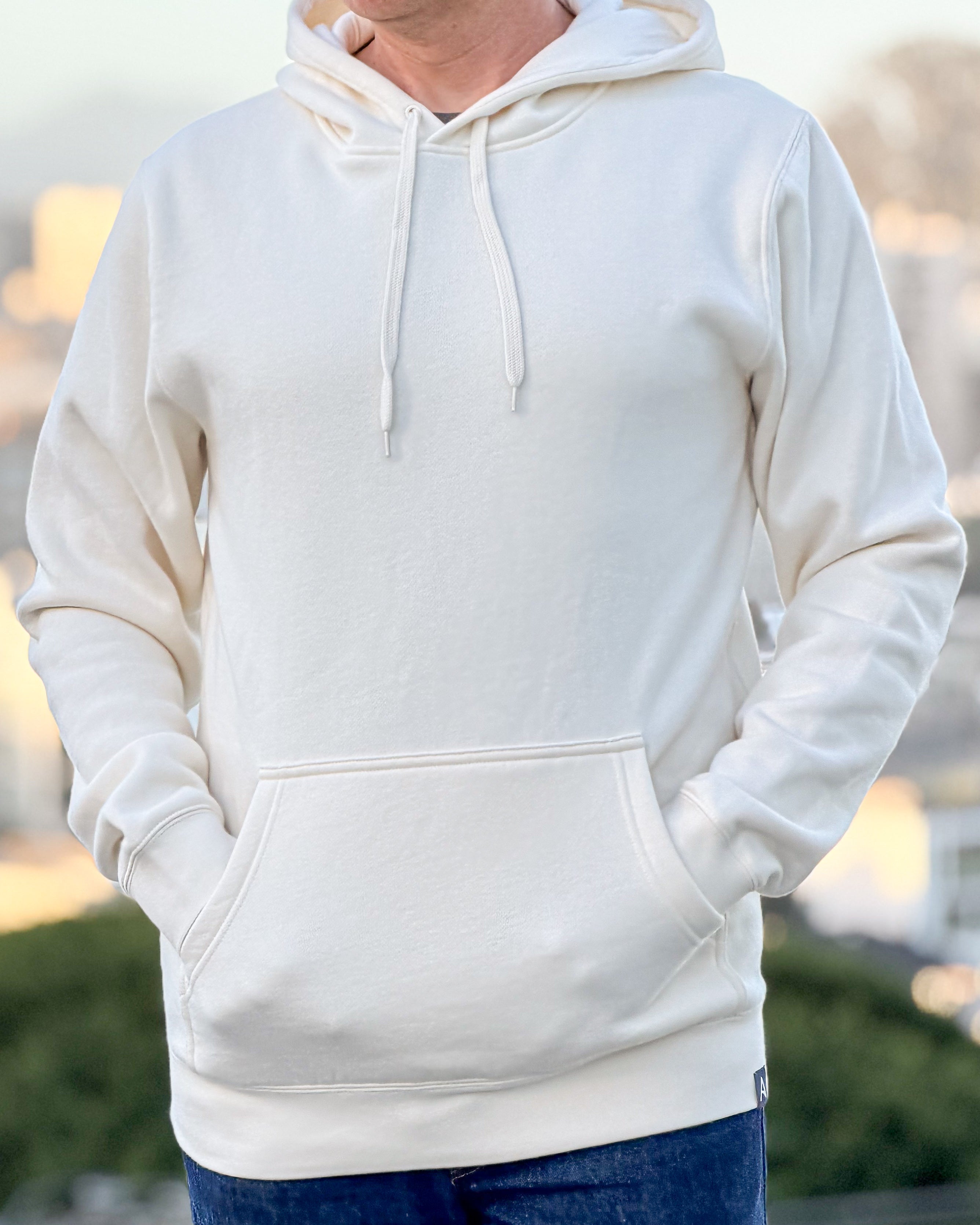 Person wearing an Avelamer Sausalito Hoodie in Mainsail off-white with a blurred background