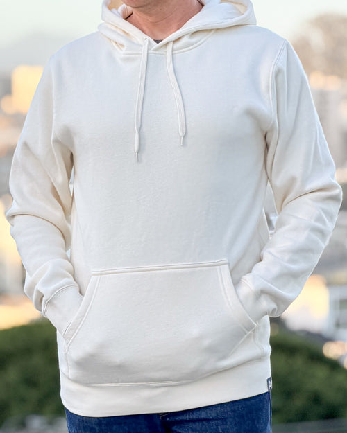 Person wearing an Avelamer Sausalito Hoodie in Mainsail off-white with a blurred background