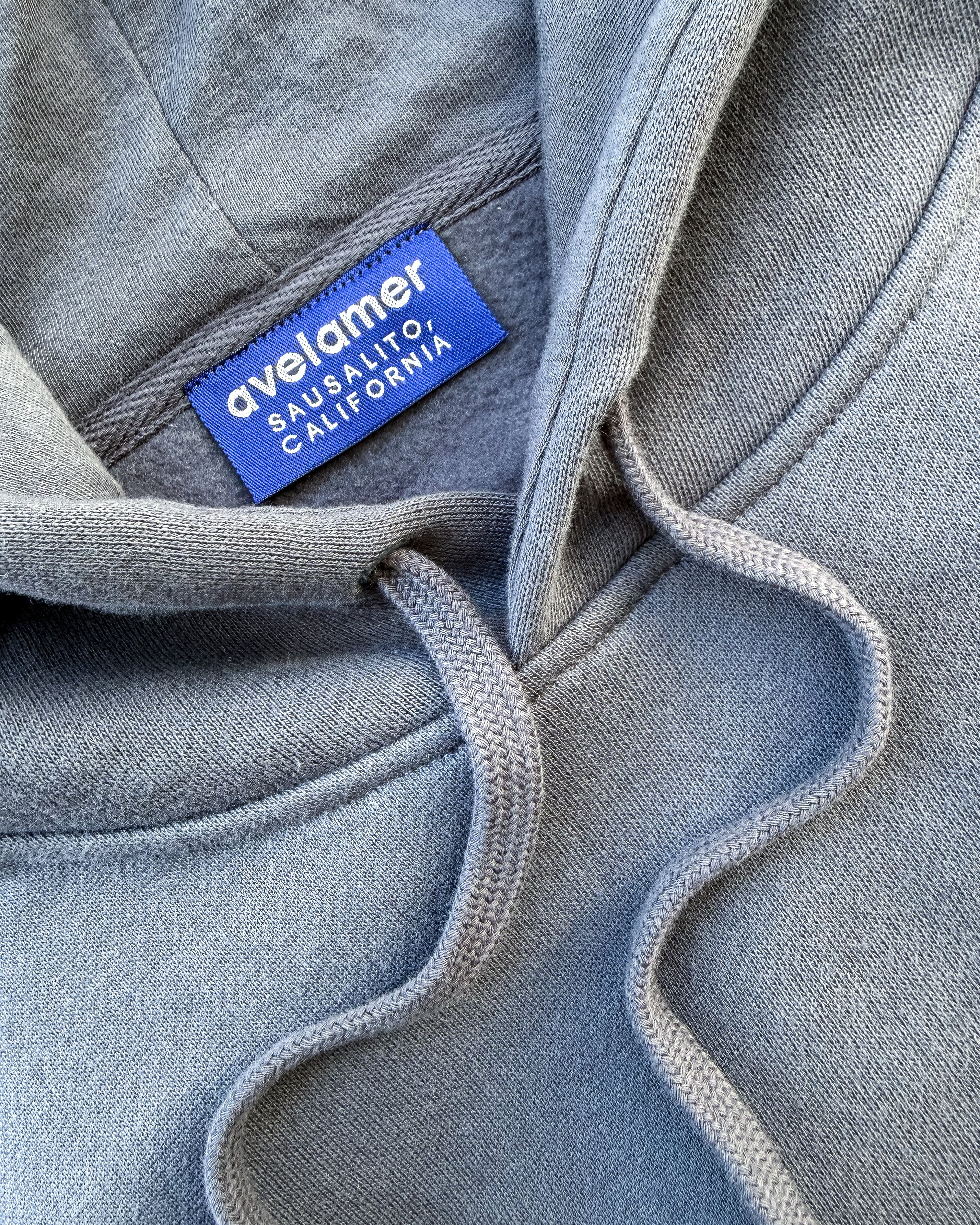 Avelamer Sausalito Hoodie in Ocean Slate (blue-gray) with an Avelamer Sausalito, California brand woven neck label visible