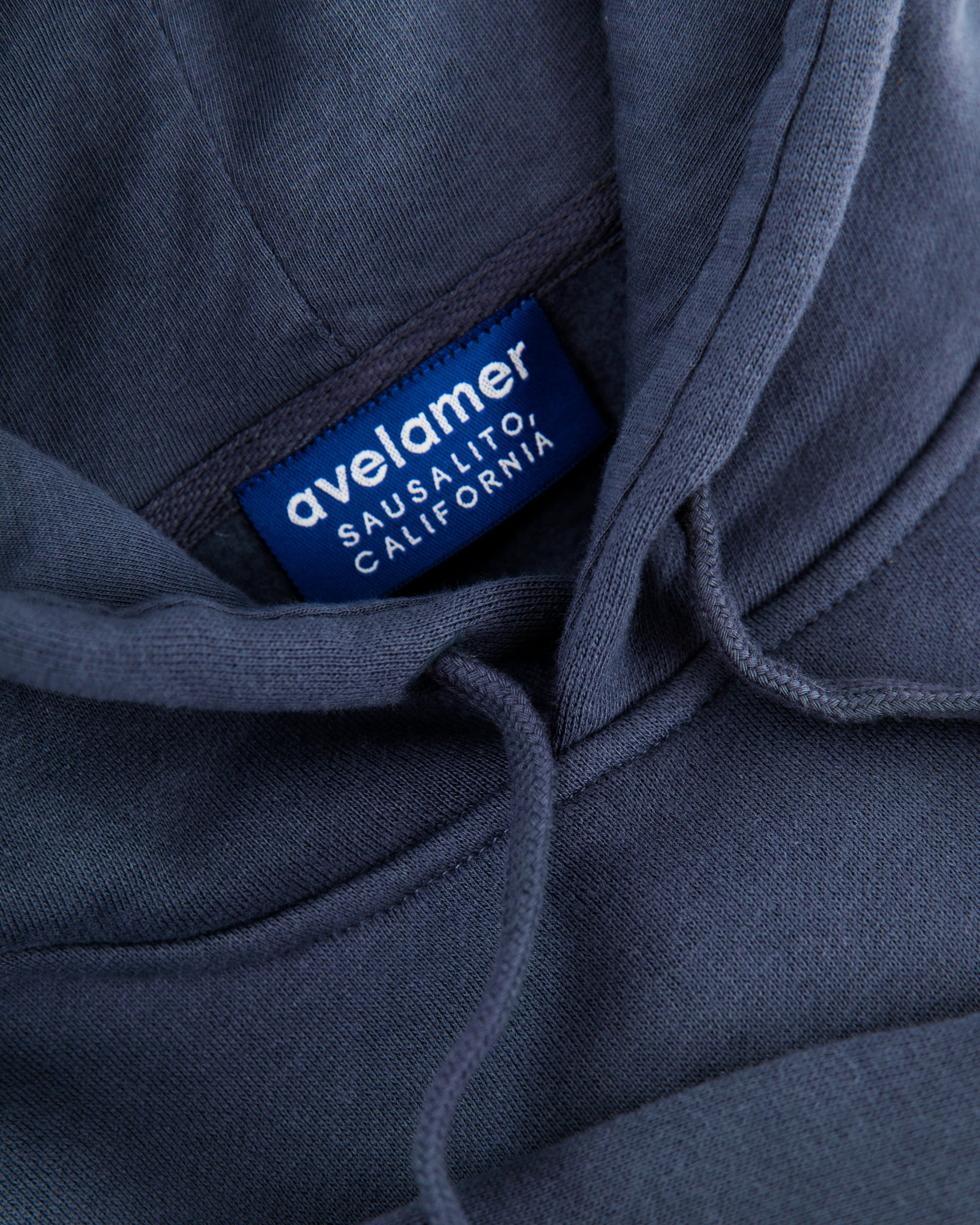 Close-up of Avelamer Sausalito Hoodie in Ocean Slate blue-gray with a woven branded neck label 