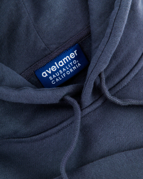 Close-up of Avelamer Sausalito Hoodie in Ocean Slate blue-gray with a woven branded neck label 