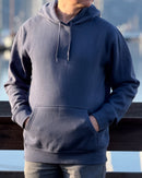 Person wearing an Avelamer Sausalito Hoodie in Ocean slate blue-gray with hands in pockets by a waterfront marina