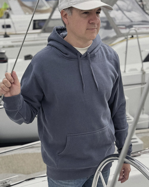 Man wearing an ocean slate blue-gray hoodie on a boat