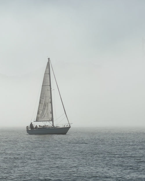 Sailboat with a large sail on a body in San Francisco Bay in heavy fog as part of the Avelamer brand world.