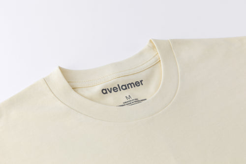 Close-up of Avelamer Spencer Long Sleeve tee in Mainsail off-white with a dark gray printed neck label.