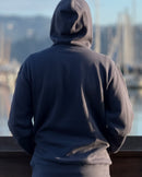 Person wearing a blue-gray hoodie with a blurred Sausalito waterfront background